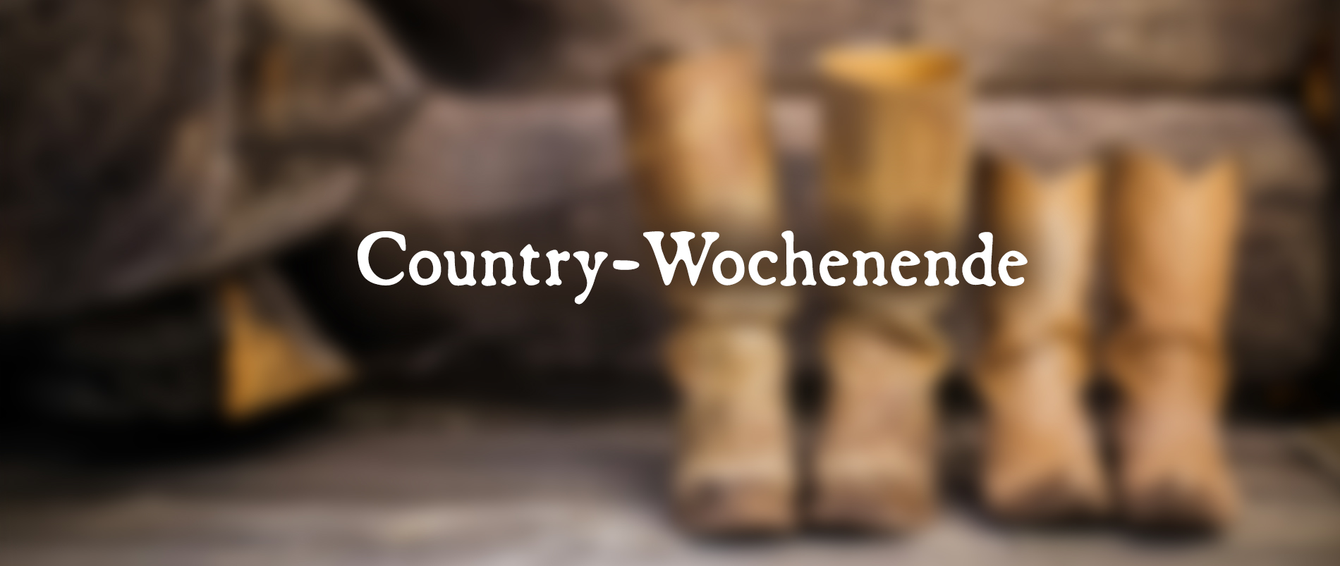 Zwei Paar Cowboy-Stiefel vor einer hölzernen Wand mit dem Text 'Country Wochenende'.