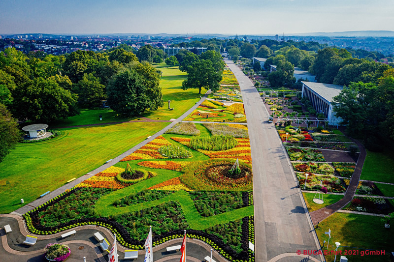 Ein blühendes Tulpenbeet im Park mit einem historischen Observatorium im Hintergrund und einem sprudelnden Brunnen.