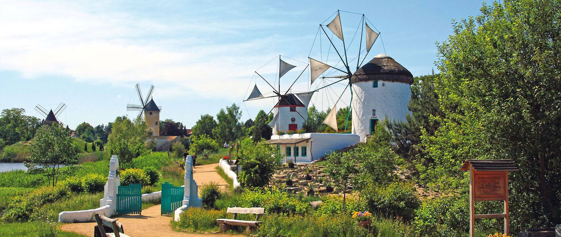 Landschaft mit mehreren Windmühlen im Grünen unter blauem Himmel