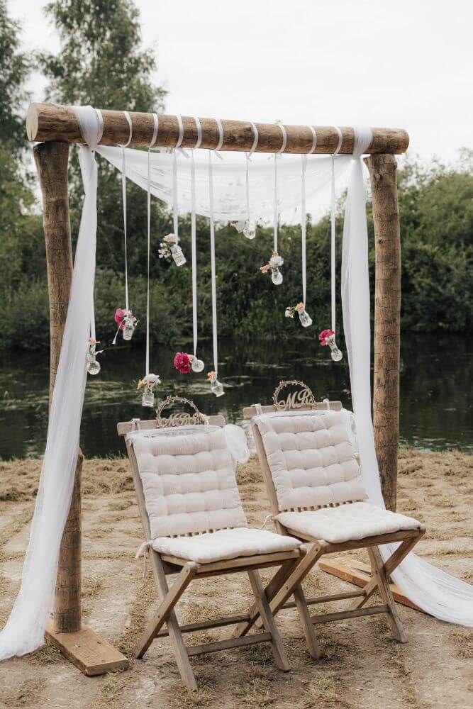 Eine dekorierte Sitzgelegenheit aus Holz für ein Hochzeitspaar vor einem See.