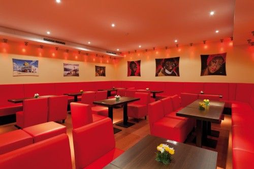 Innenraum eines modern gestalteten Cafés mit roten Sitzmöbeln und dekorativer Wandkunst.
