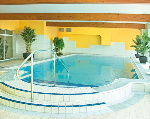 Innenpool mit blauen Kacheln und Pflanzen am Rand