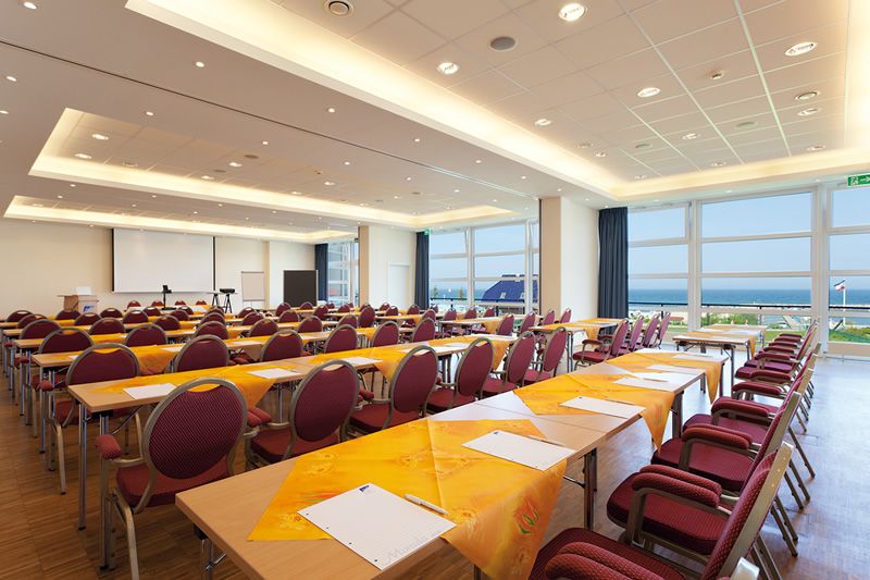 Großer, heller Konferenzraum mit Stuhlreihen und gedeckten Tischen, Blick aufs Meer.